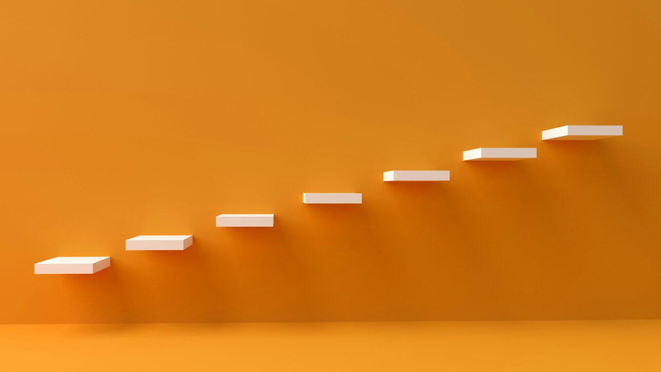 White floating rectangular shelves ascend diagonally along a smooth orange wall, casting soft shadows onto a matching orange floor in a minimalist interior.